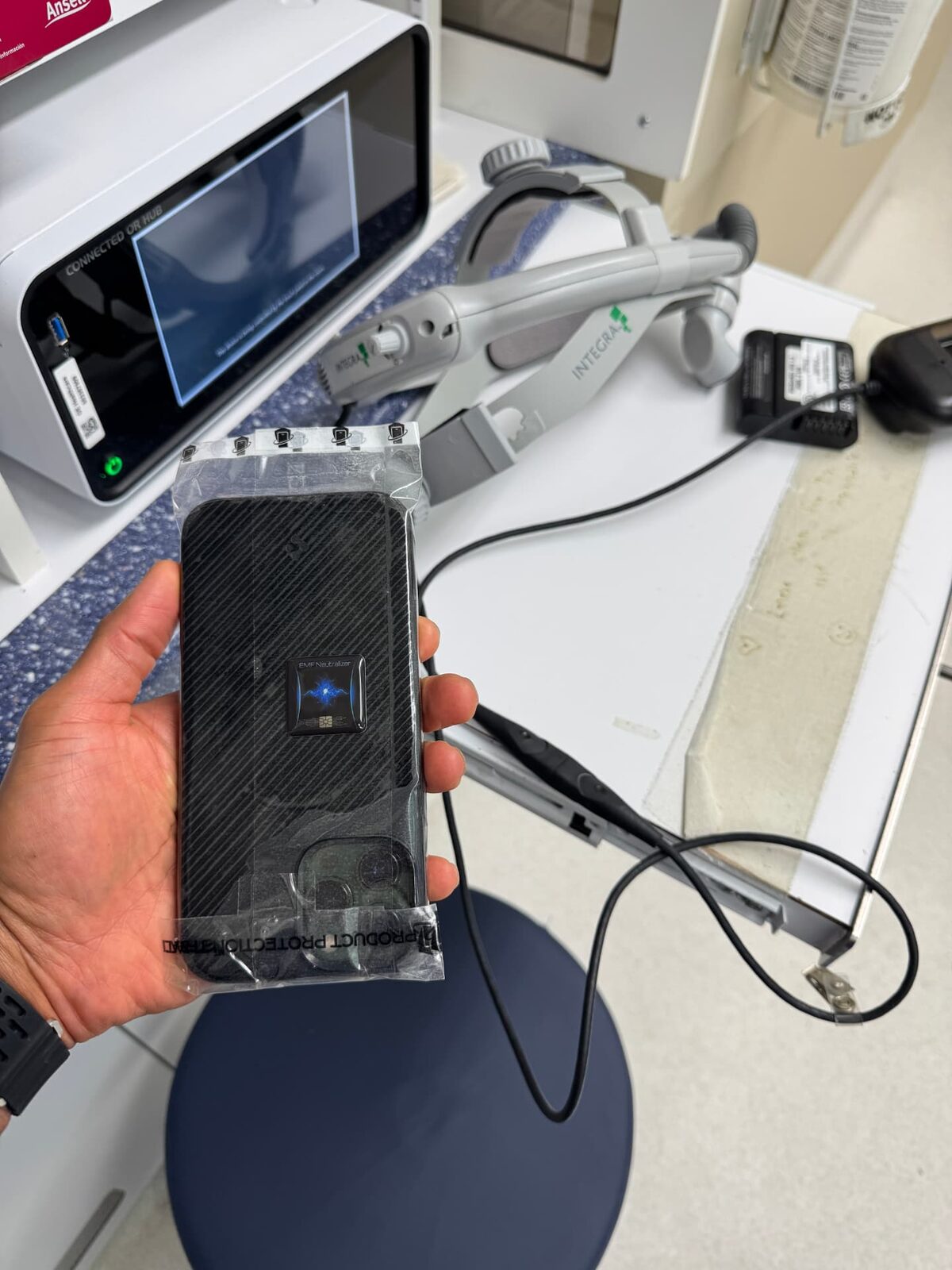 WynnShield™-wrapped phone held beside surgical equipment in a clinic