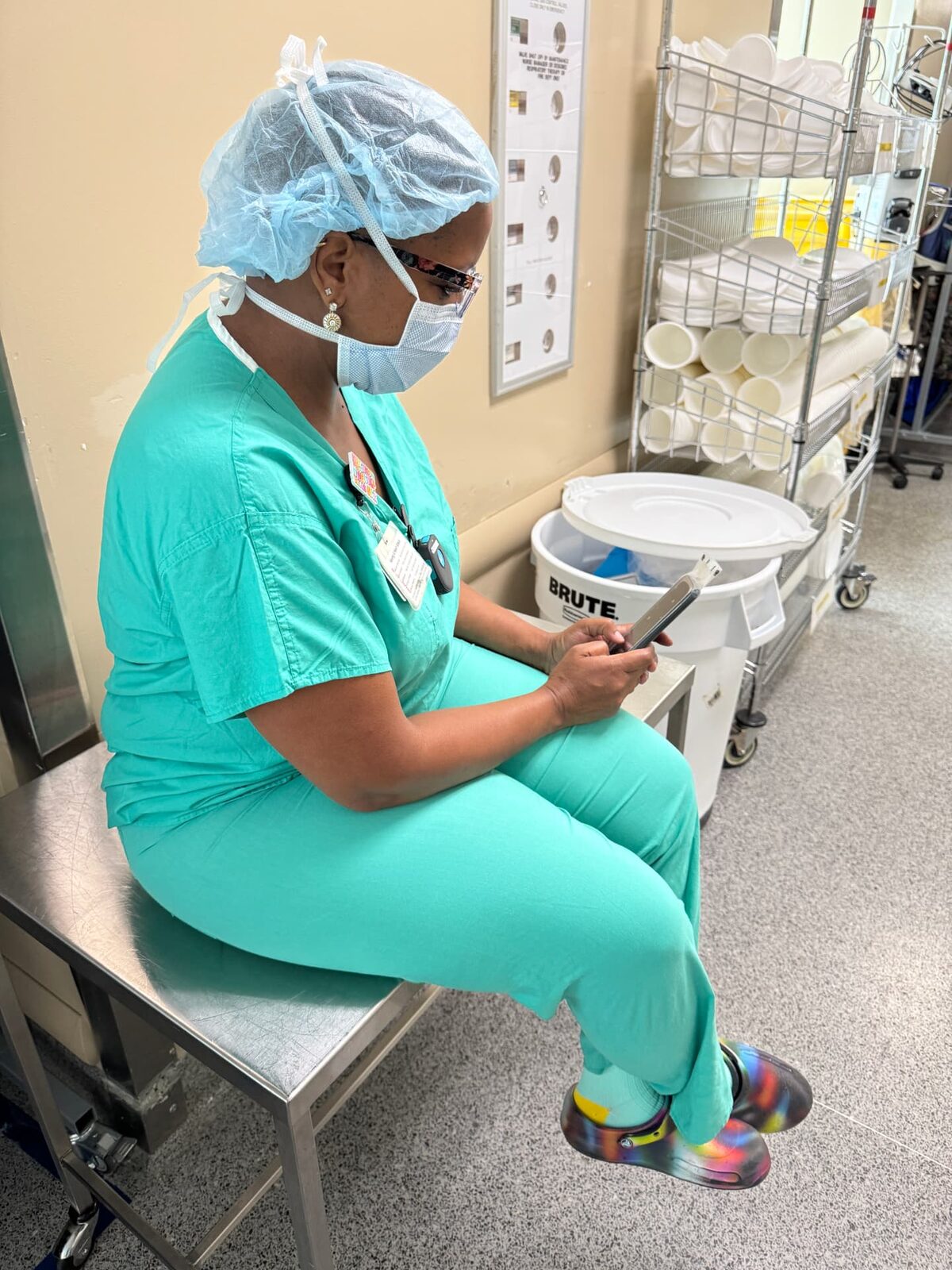 Operating room nurse in scrubs using a WynnShield™-wrapped phone