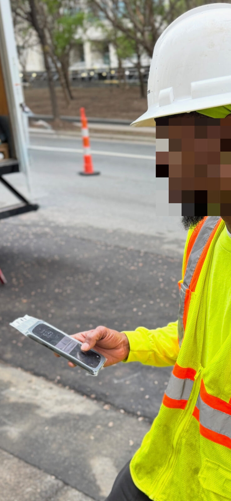 Road crew worker using a WynnShield™-wrapped phone on a jobsite